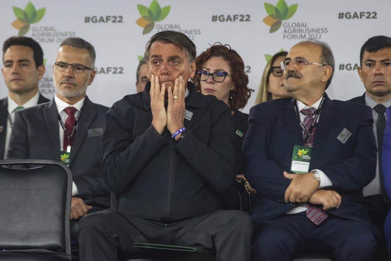 Jair Bolsonaro passando as mãos no rosto com cara de preocupado durante evento.