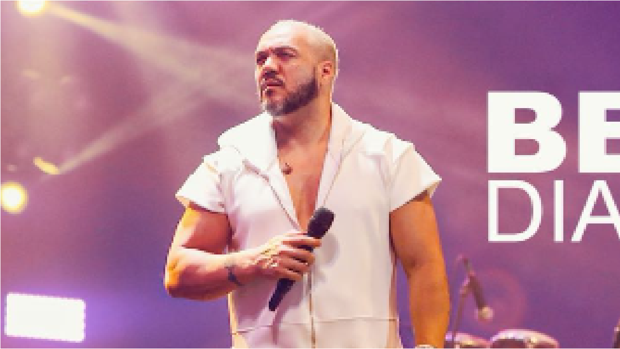 Cantor Belo em palco segurando um microfone com sua mão direita.