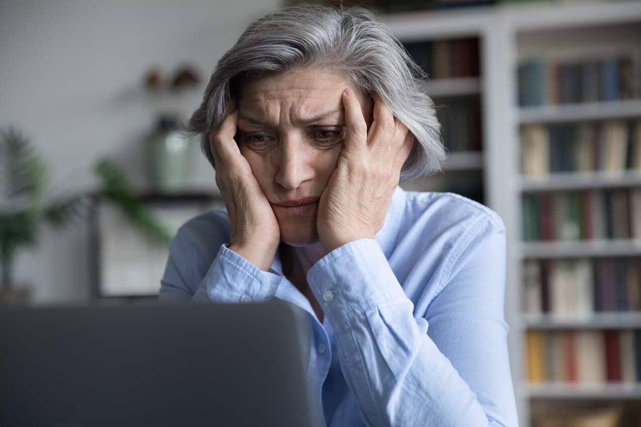 Mulher idosa com expressão de preocupação, em frente à um computador