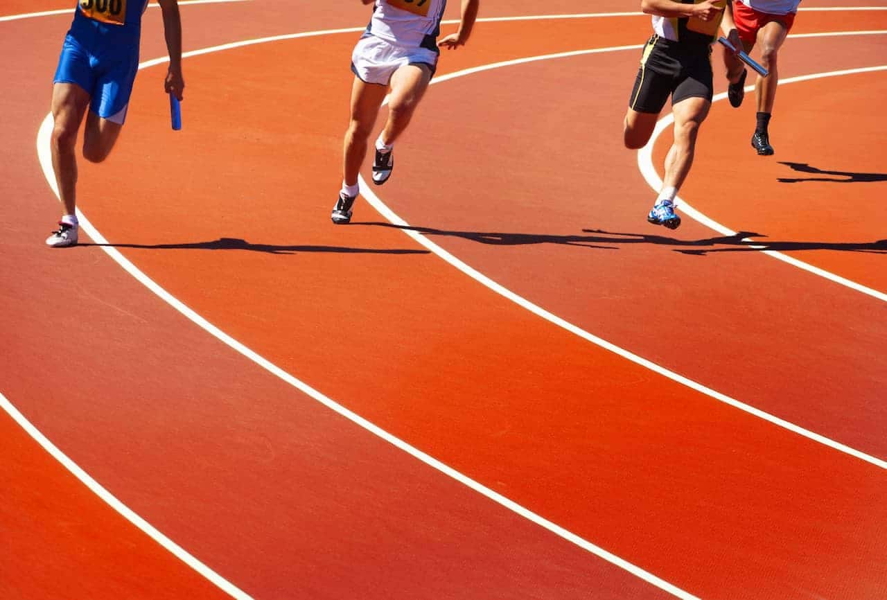 Quatro velocistas em uma pista de atletismo