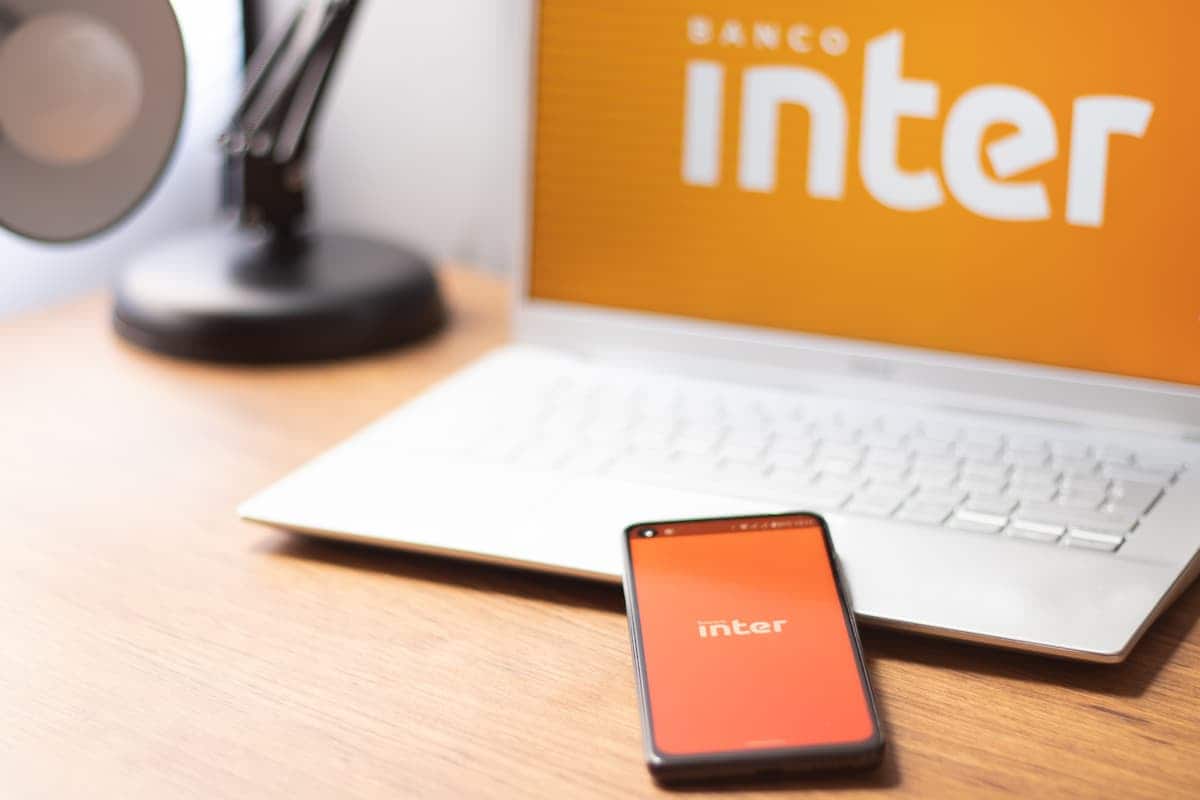 Aplicativo Inter em celular e notebook sobre mesa.