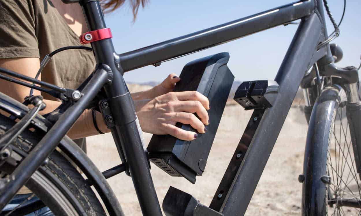 Pessoa colocando uma bateria em uma bicicleta elétrica trânsito