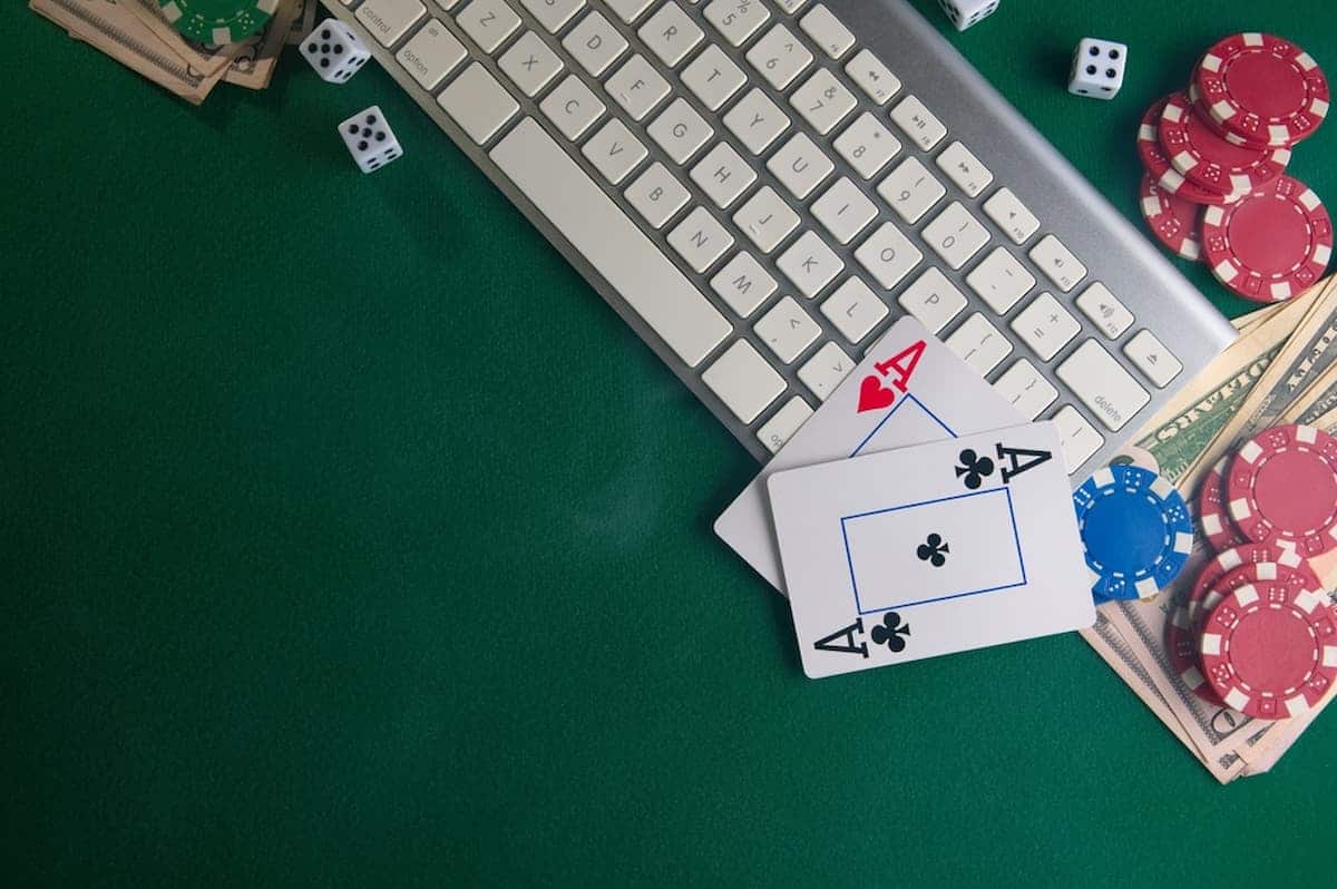 Imagem de uma mesa com teclado, fichas de poker e cartas de baralho apostas