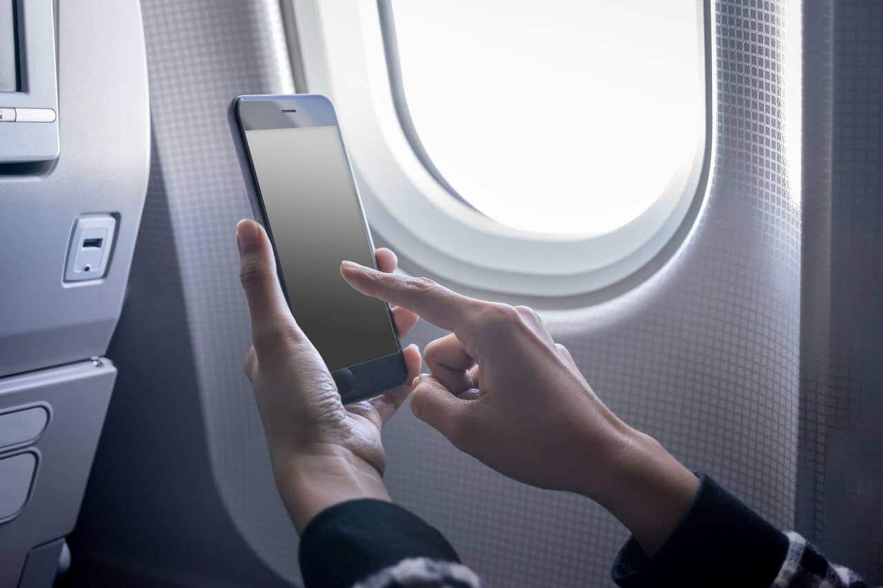 Mãos mexendo no celular dentro de um avião