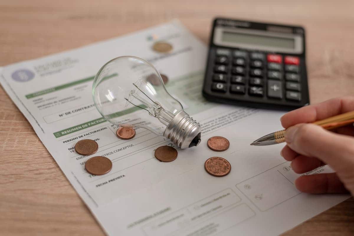 Conta de luz com lâmpada, moedas e calculadora sobre mesa