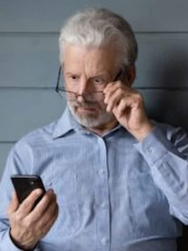Homem idoso olhando para o celular com cara de assombro