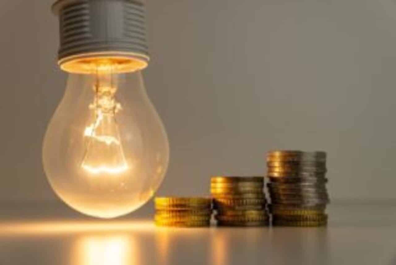 Imagem de uma lâmpada e de moedas, remetendo à conta de luz.