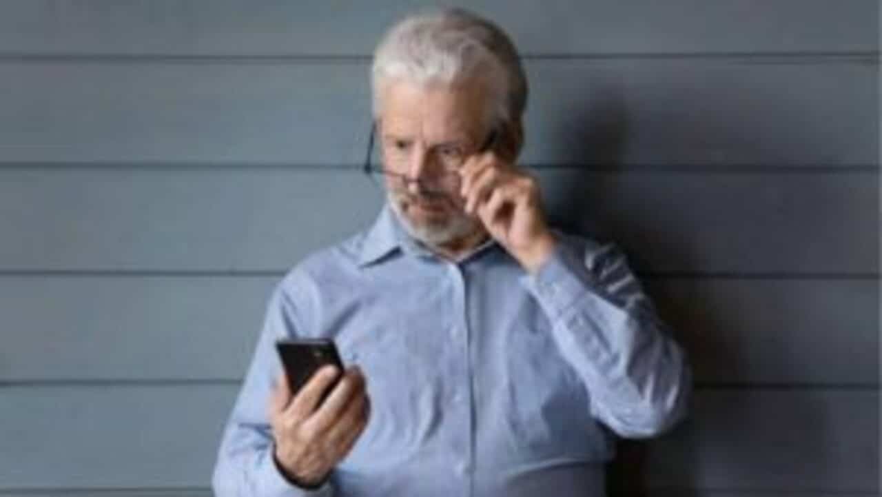 Idoso olhando desconfiado para o celular