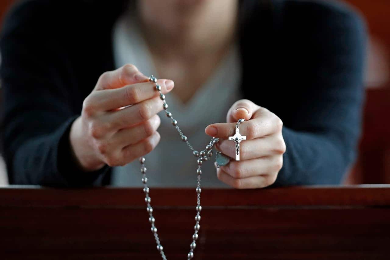 mãos segurando terço