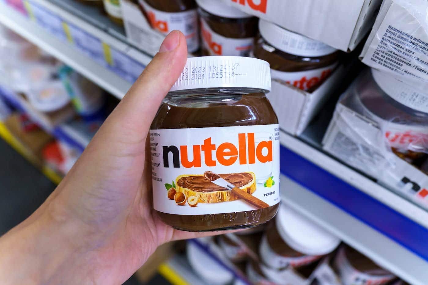 Foto mostra uma pessoa segurando um pote de Nutella.