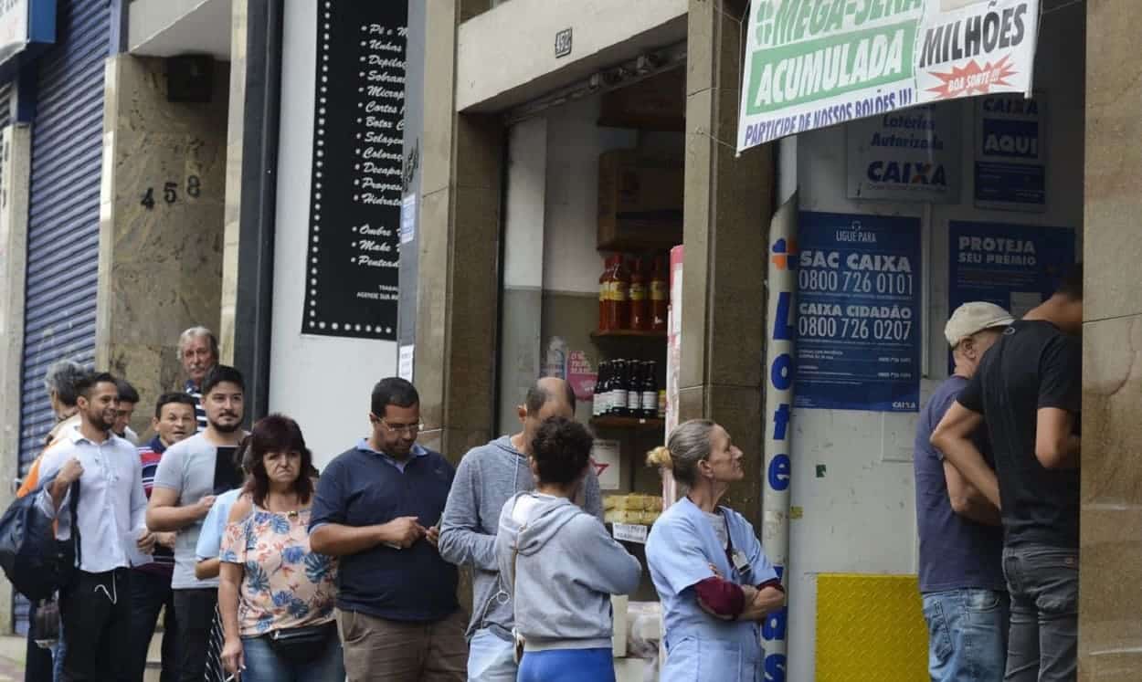 Pessoas na fila para entrar em uma Casa Lotérica