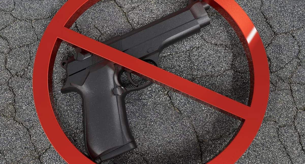 Símbolo de pare sobreposto em imagem de uma arma de fogo.