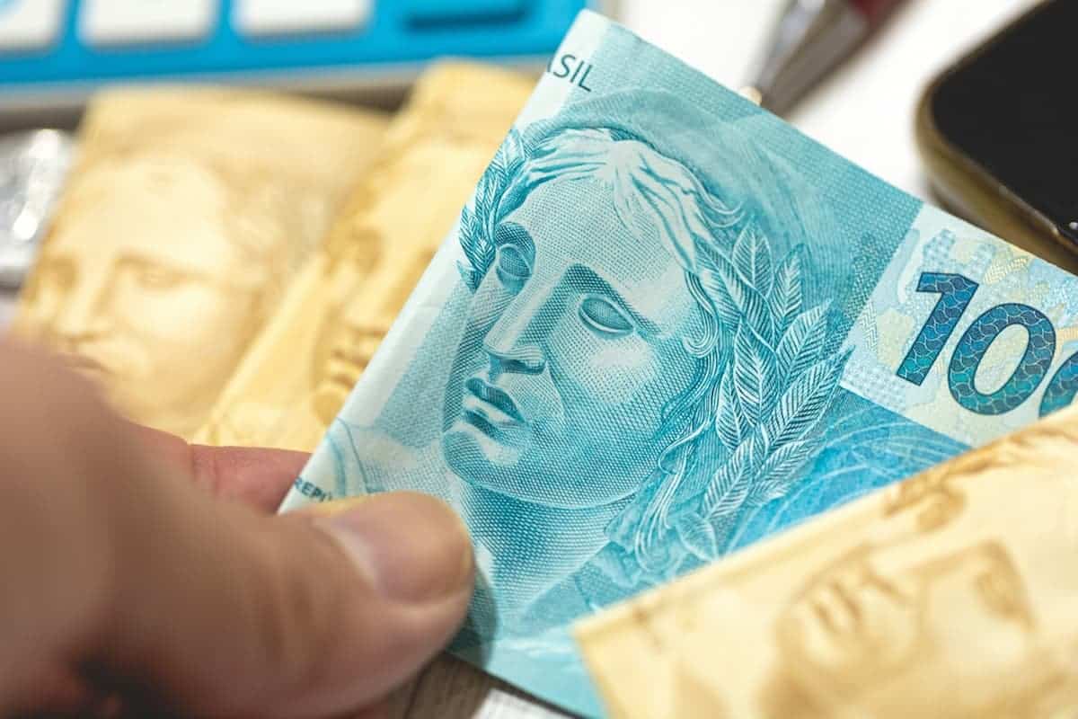 Imagem de pessoa segurando reais.