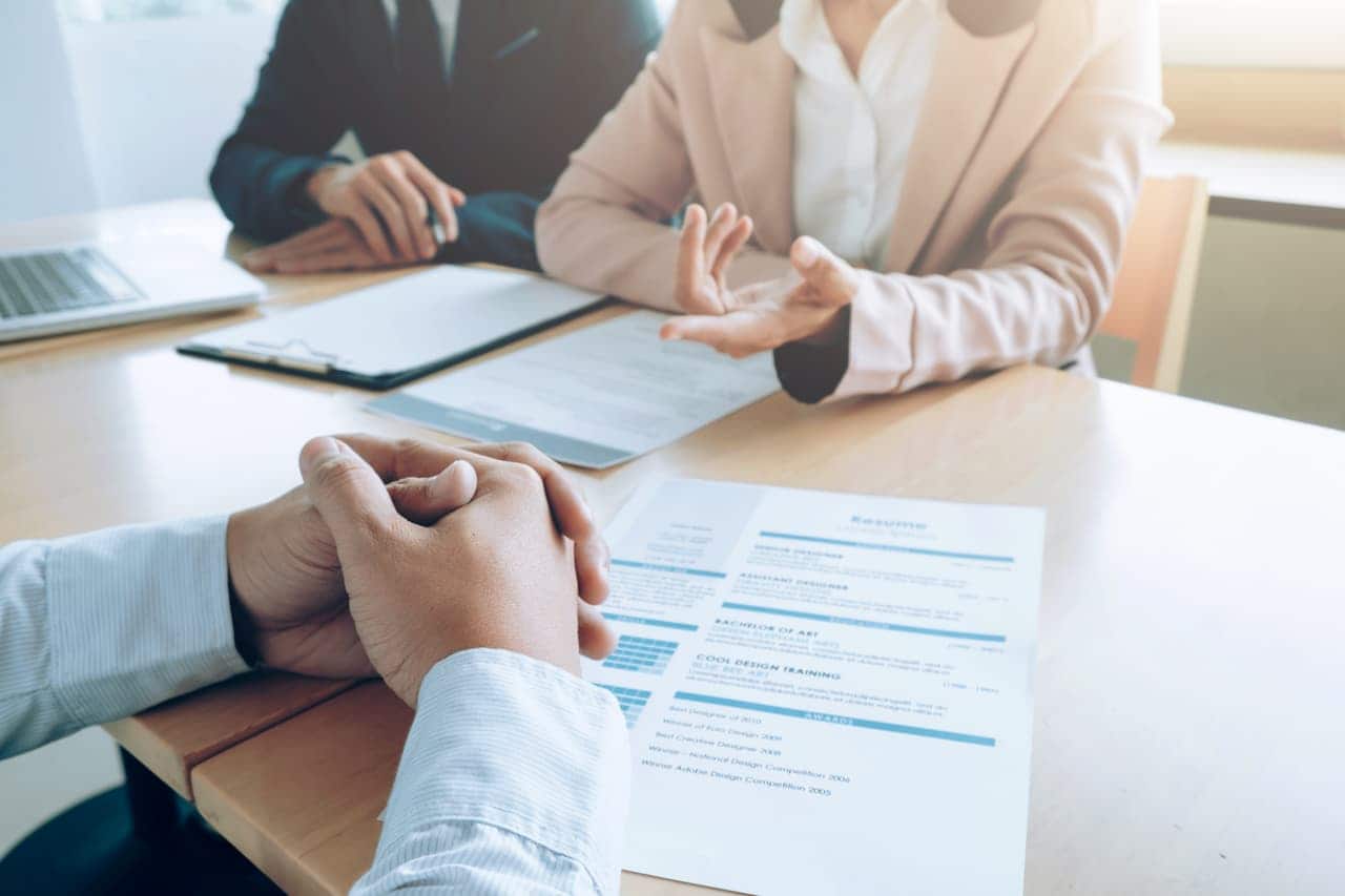 A imagem mostra um recrutador fazendo entrevistas de processo seletivo sesc. Além de currículos sobre a mesa.