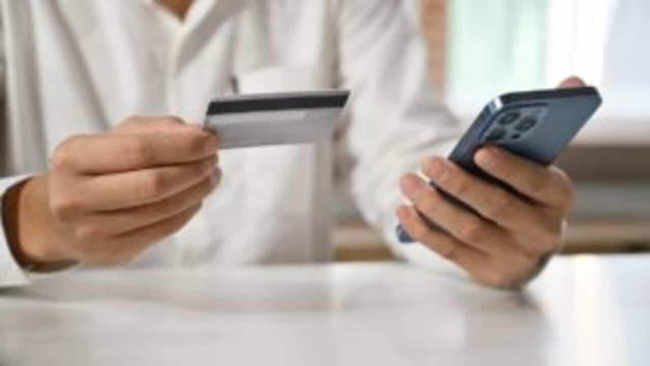 Cliente de banco segurando cartão e celular