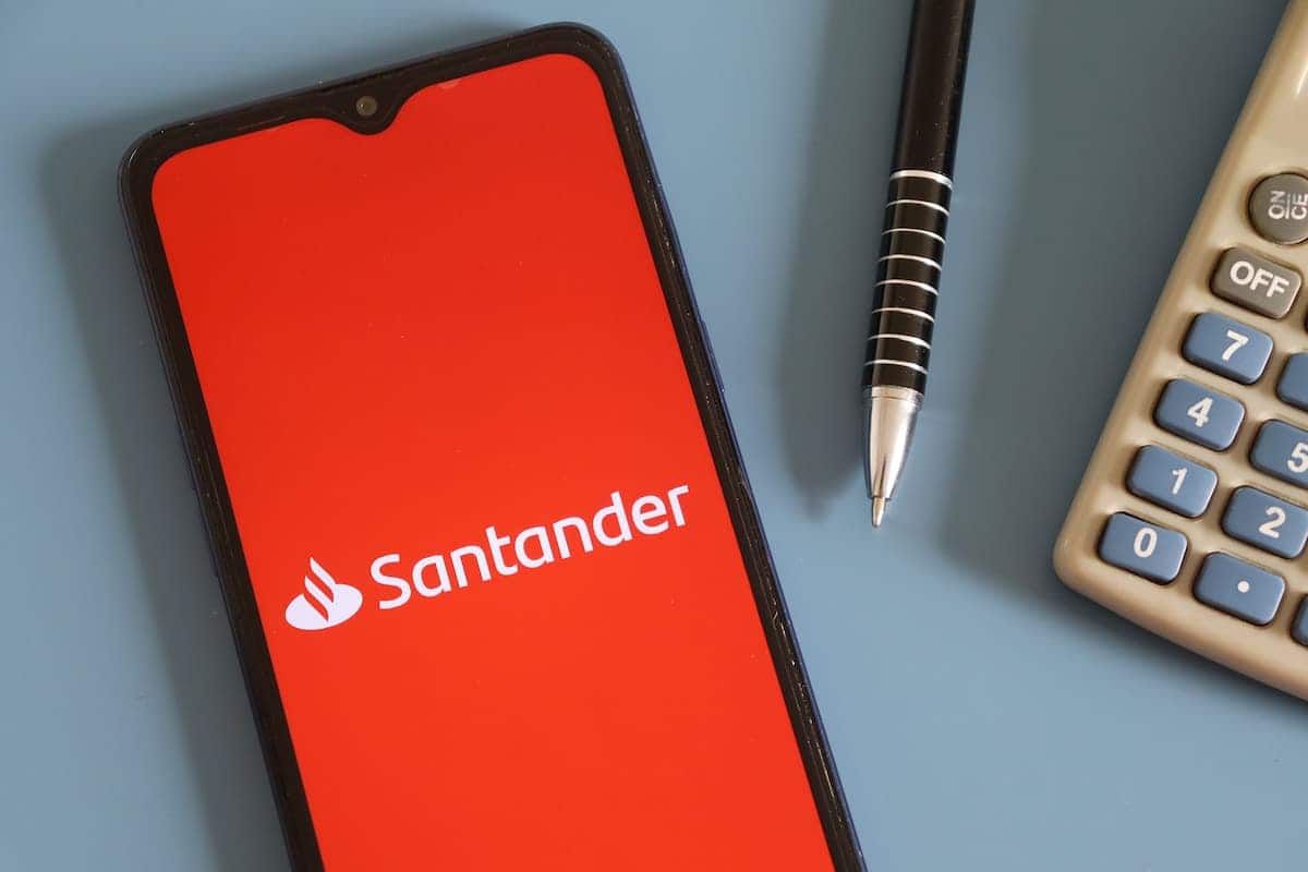 Aplicativo Santander em celular ao lado de materiais de escritório.