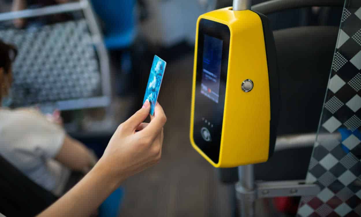 Mulher usando cartão para pagar passagem de ônibus em transporte público