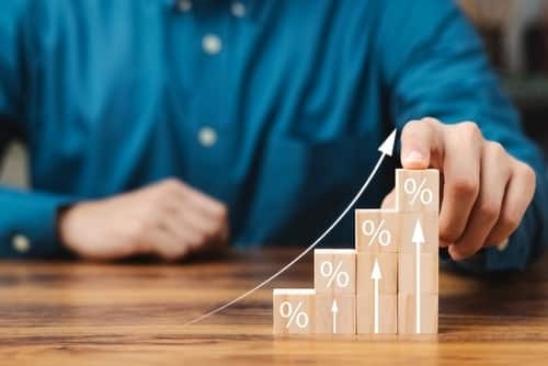 mão em gráfico em cima da mesa representando o impacto do aumento juros nos bancos