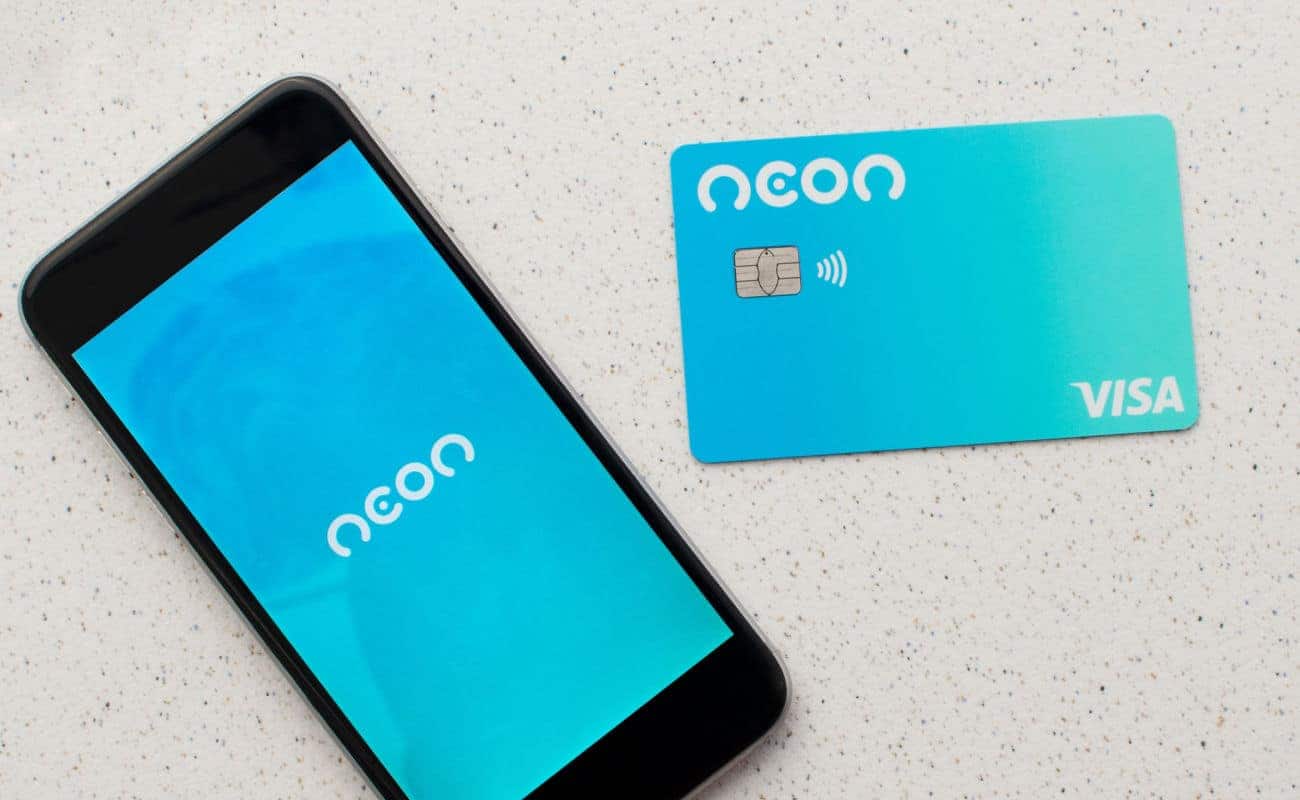 Celular com a logo na Neon na tela ao lado de um cartão da fintech