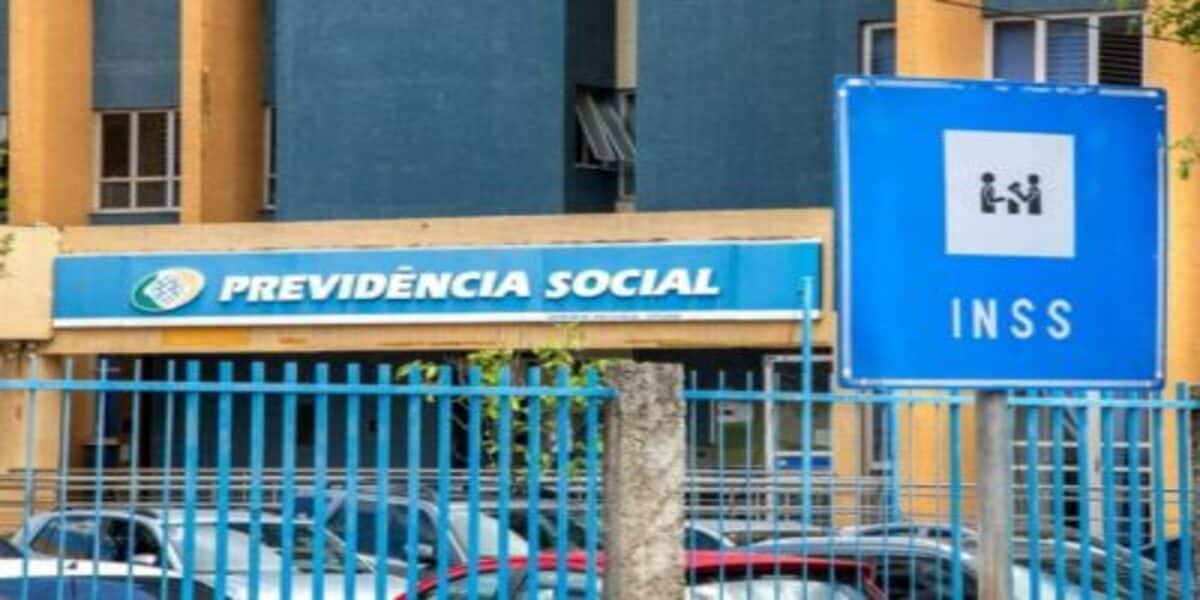Fachada da Previdência Social com uma placa do INSS em frente.