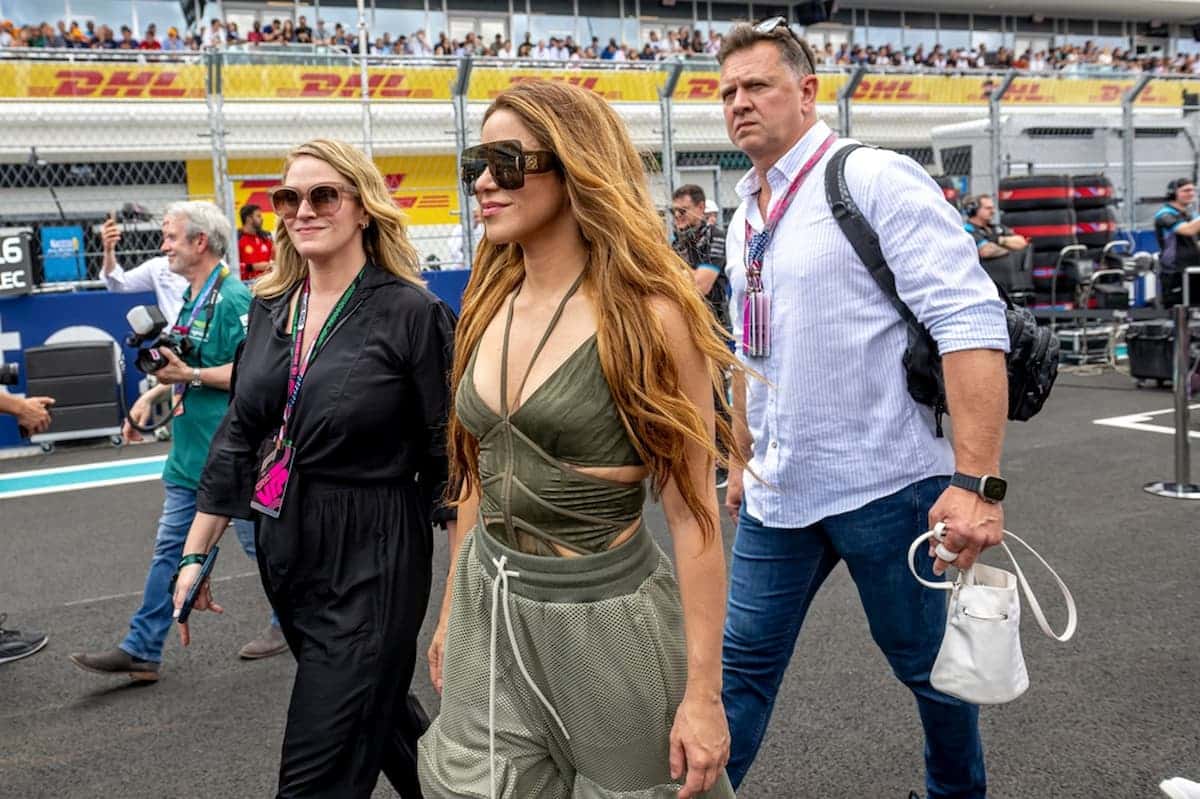 Cantora colombiana Shakira andando em pista de F1, acompanha de um homem e uma mulher.