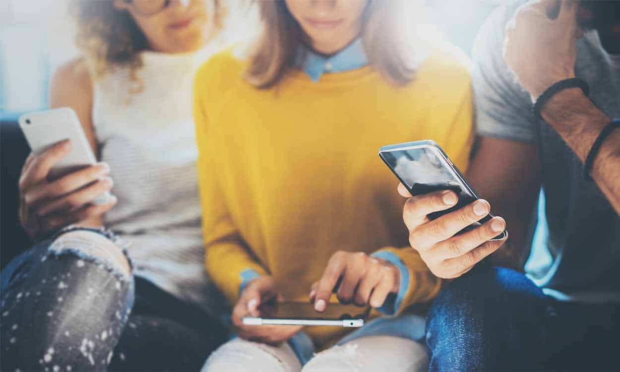 Na imagem, pessoas segurando celulares