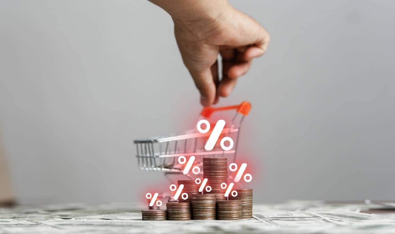 Imagem de um carrinho de mercado em miniatura e moedas com o símbolo "%"