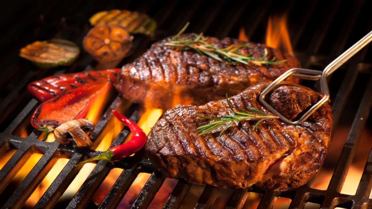 Churrasco na grelha sendo assado à base de carvão