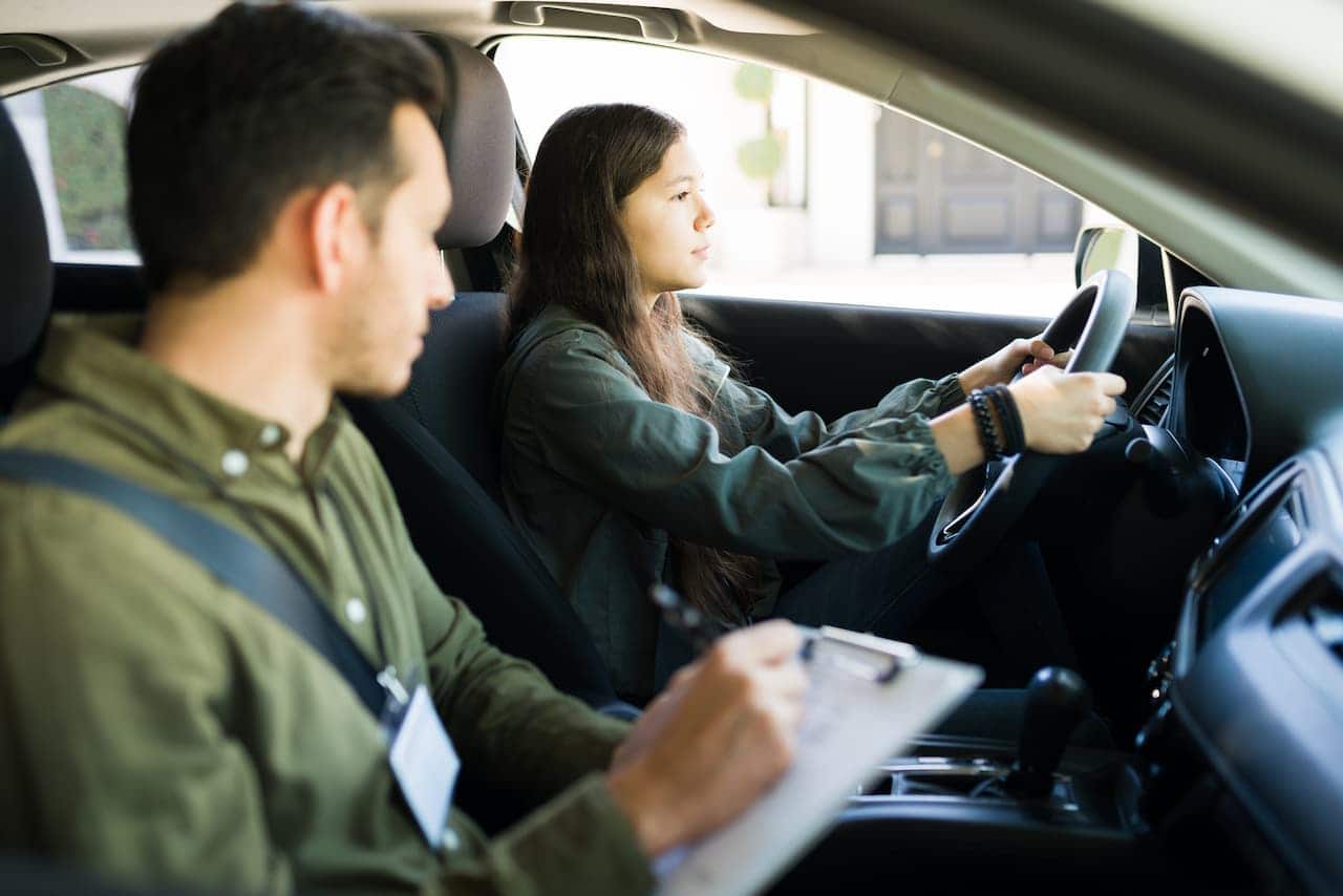 Aluna ao volante ao lado de professor de autoescola