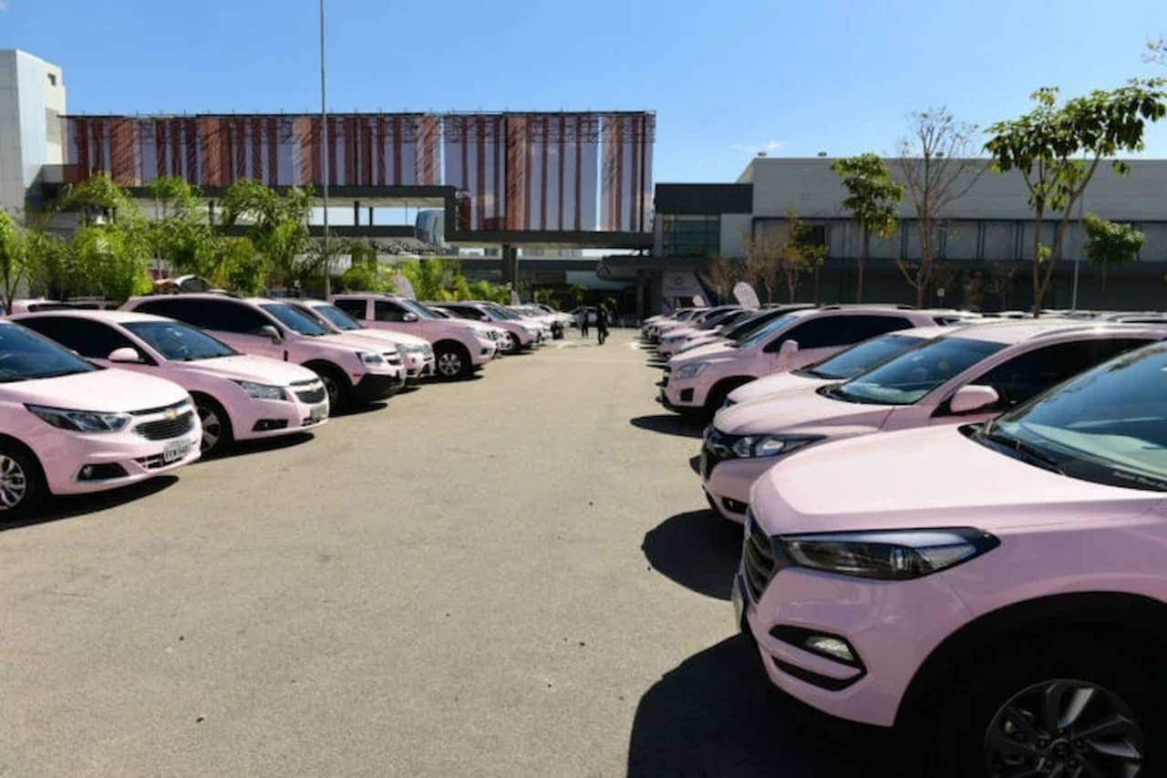 Fila de carros rosas da Mary Kay em um estacionamento.