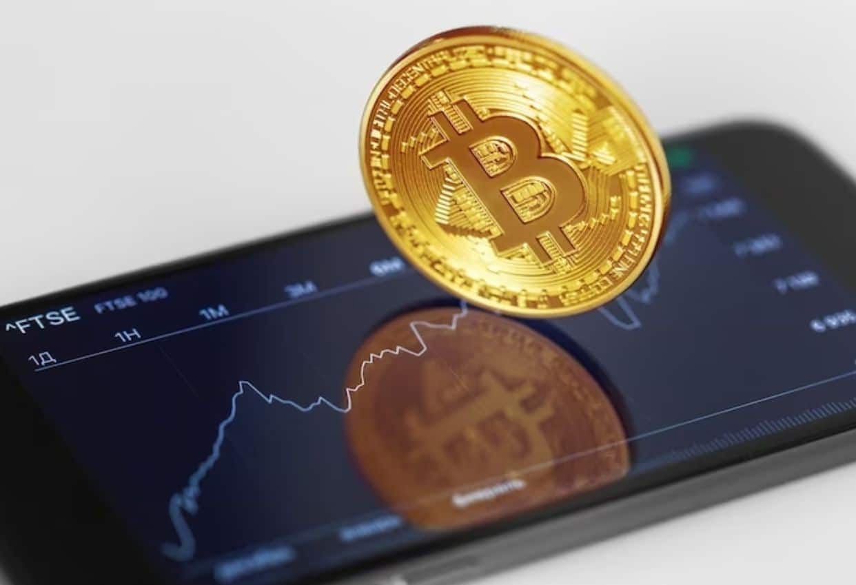 Imagem de uma celular com gráficos e uma criptomoeda