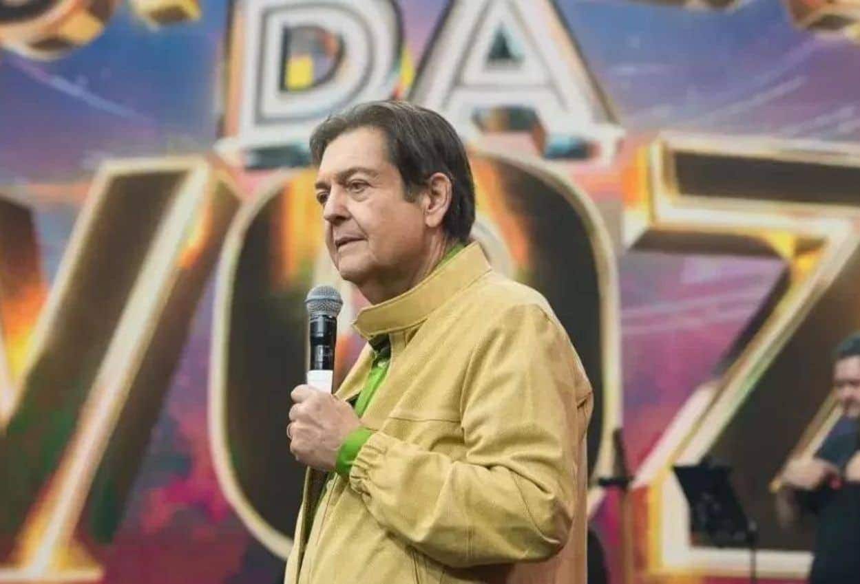 Faustão segurando o microfone enquanto apresenta o seu programa de TV.