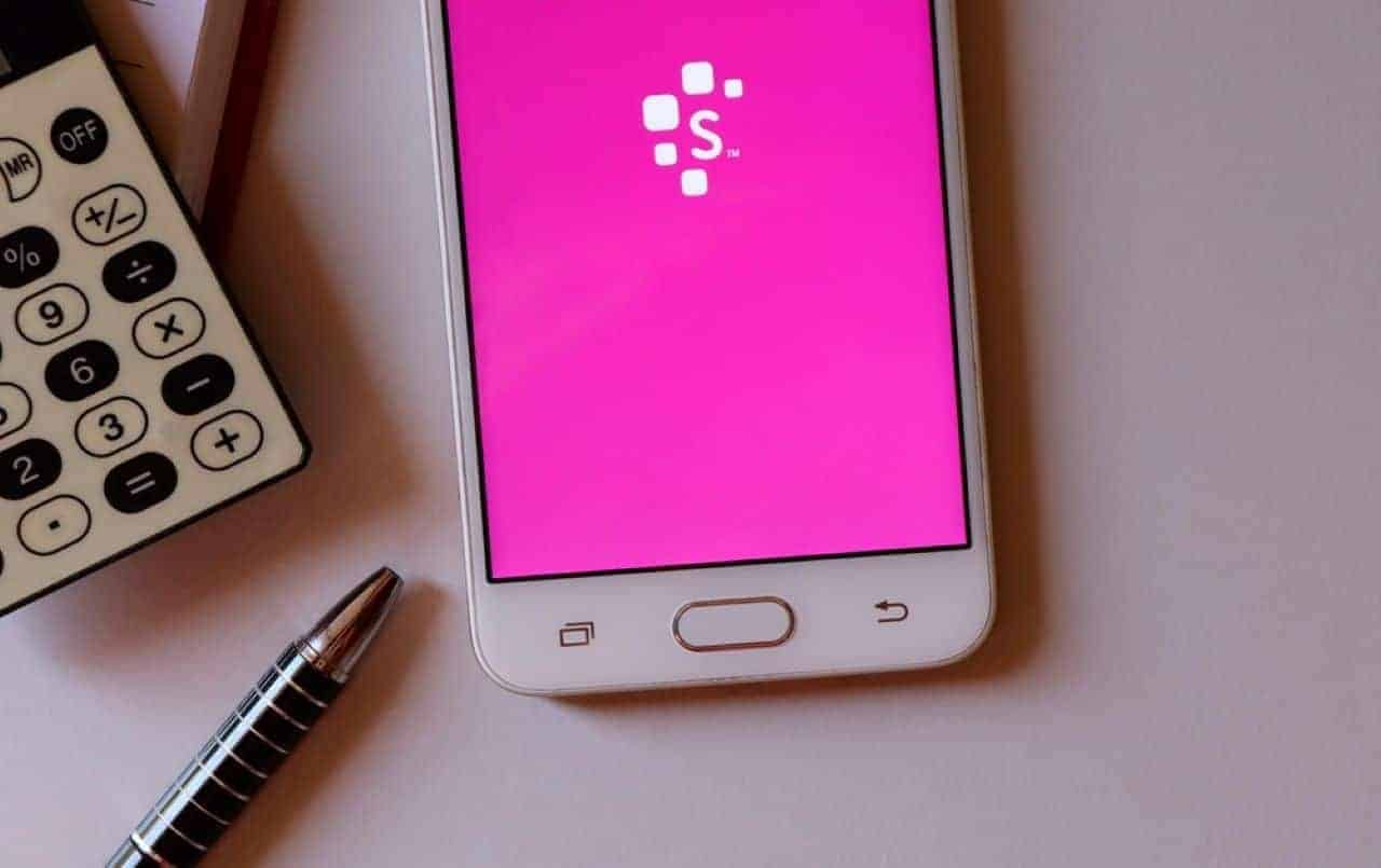 Na imagem, mesa com calculadora, caneta e celular com o aplicativo Serasa aberto