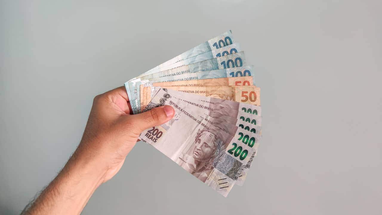 Mão segurando várias notas de dinheiro