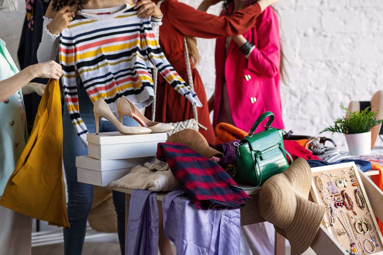 A imagem mostra um bazar de roupas, com algumas roupas em uma cadeira e outros objetos ao lado.