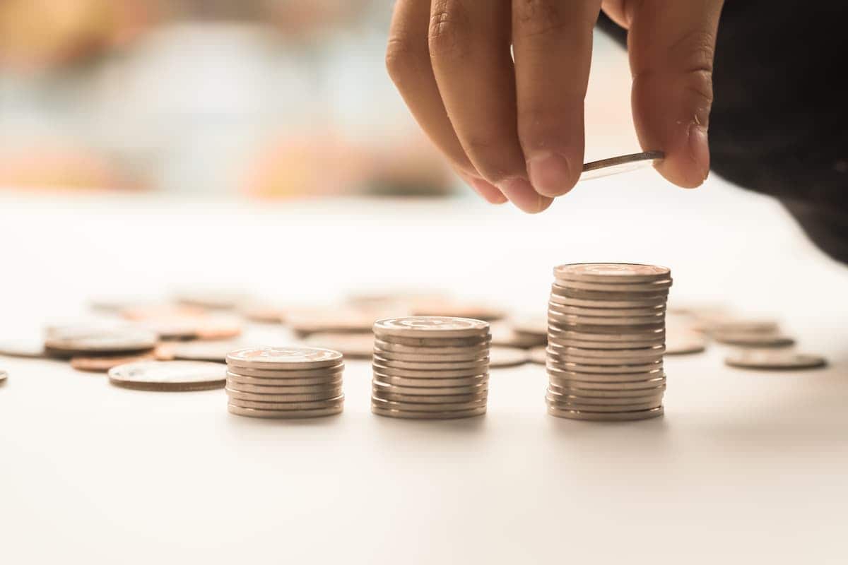 Mão de criança colocando moedas na pilha de moedas