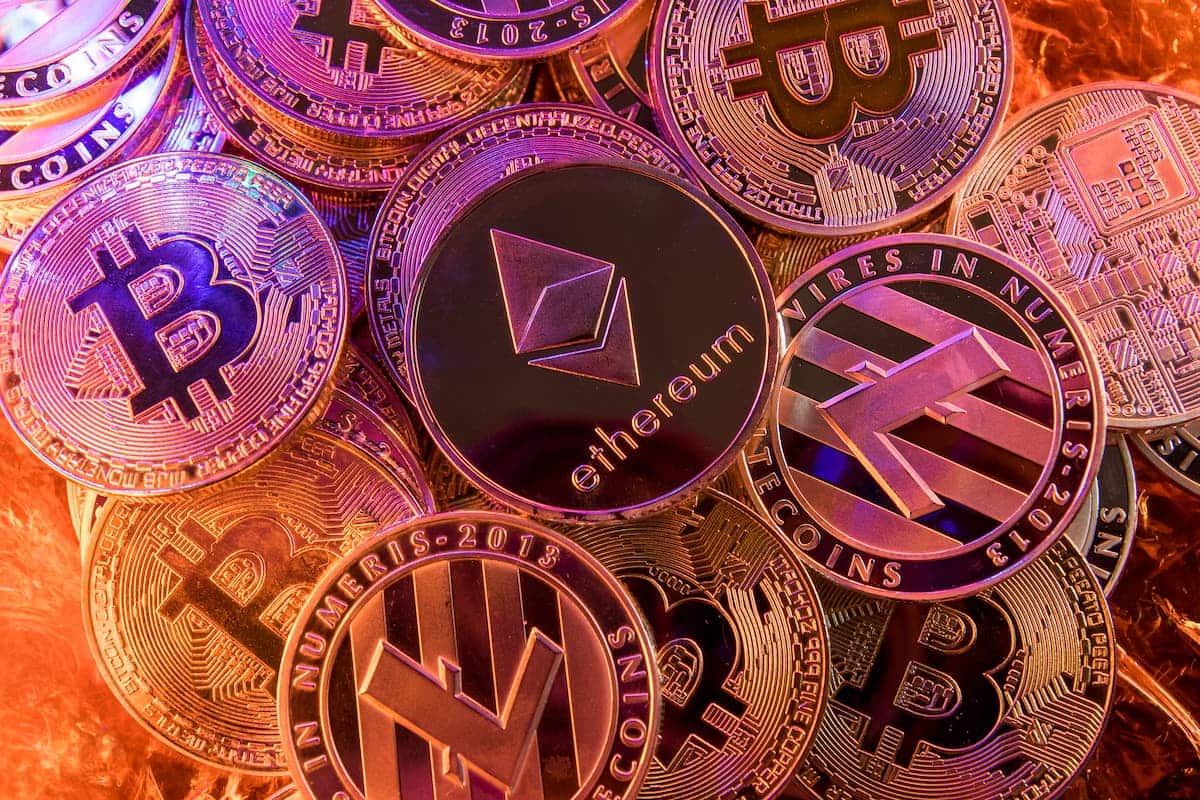 Criptomoedas empilhadas sobre mesa com diversos nomes criptomoeda