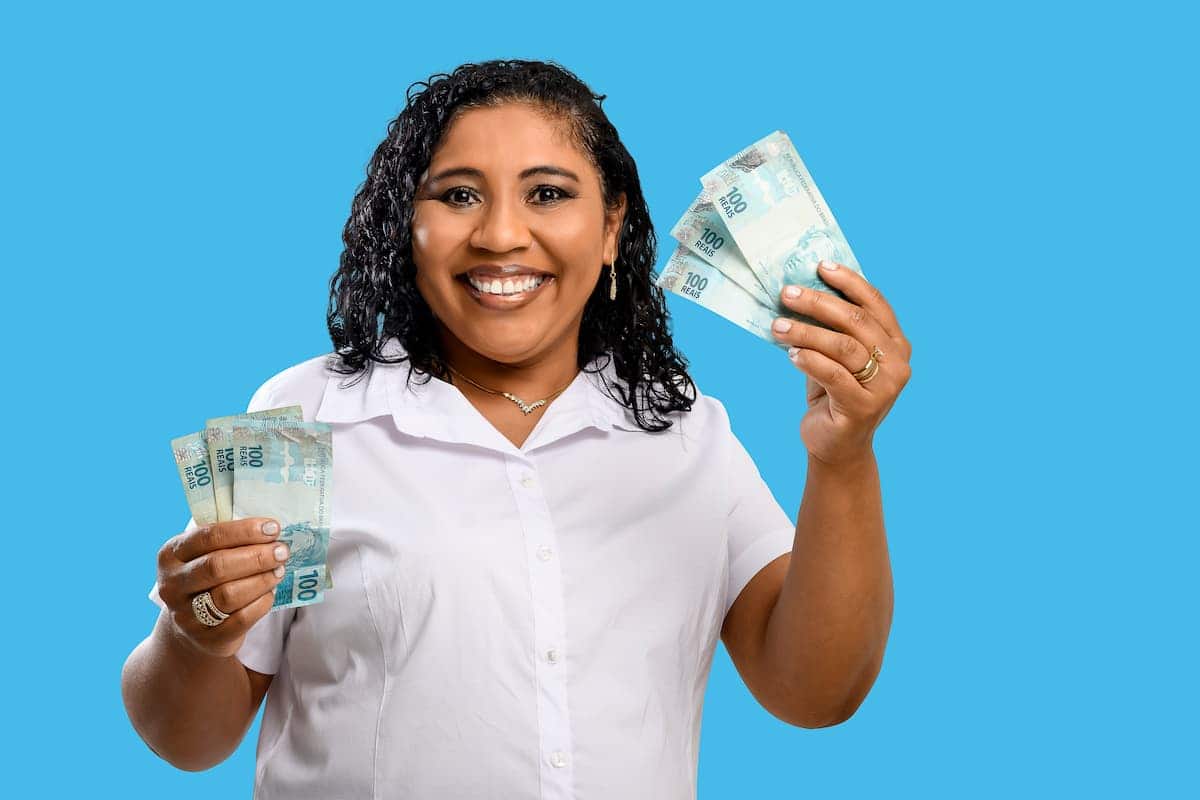 Mulher segurando notas de R$ 100