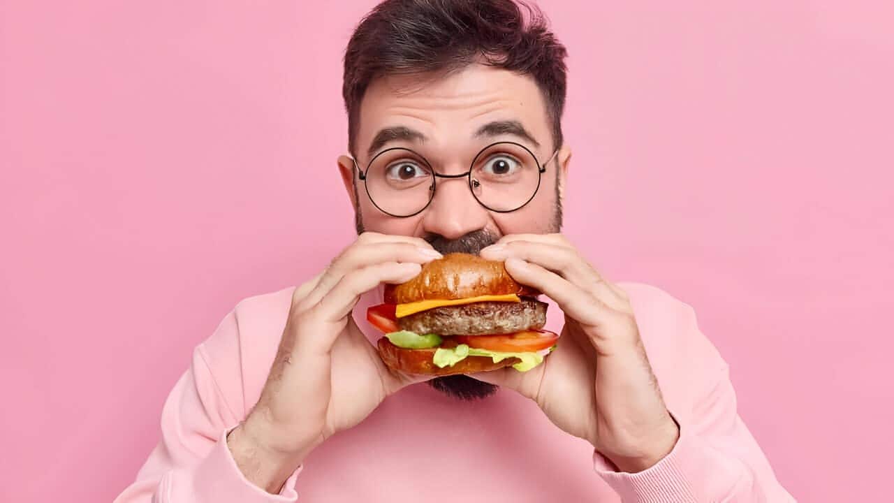 Homem mordendo lanche de rede de fast-food.