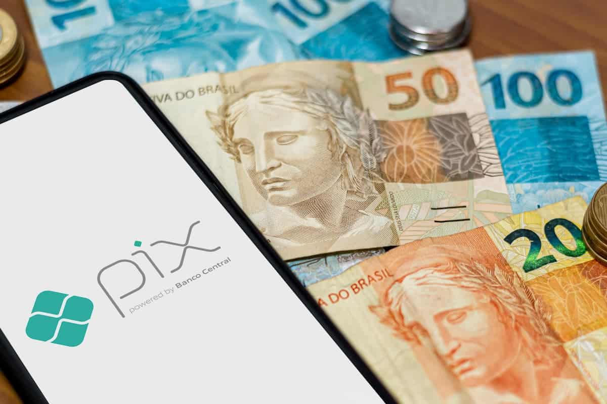 Celular com Pix na tela e notas de dinheiro ao redor