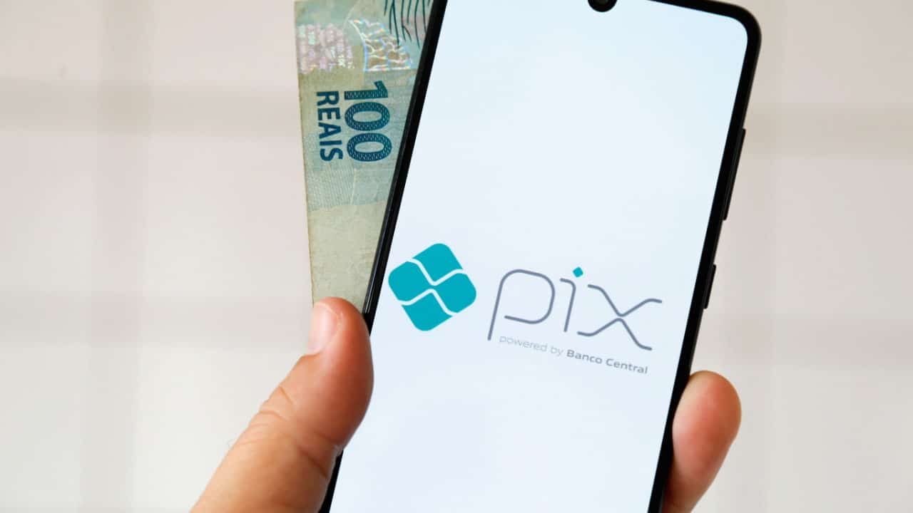 Celular com emblema do Pix e nota de R$ 100 atrás do aparelho