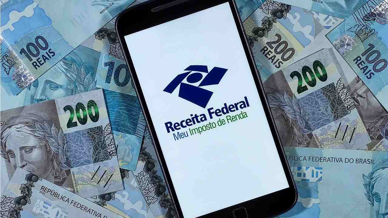 No centro de notas de 100 e 200 reais, celular com logo da Receita