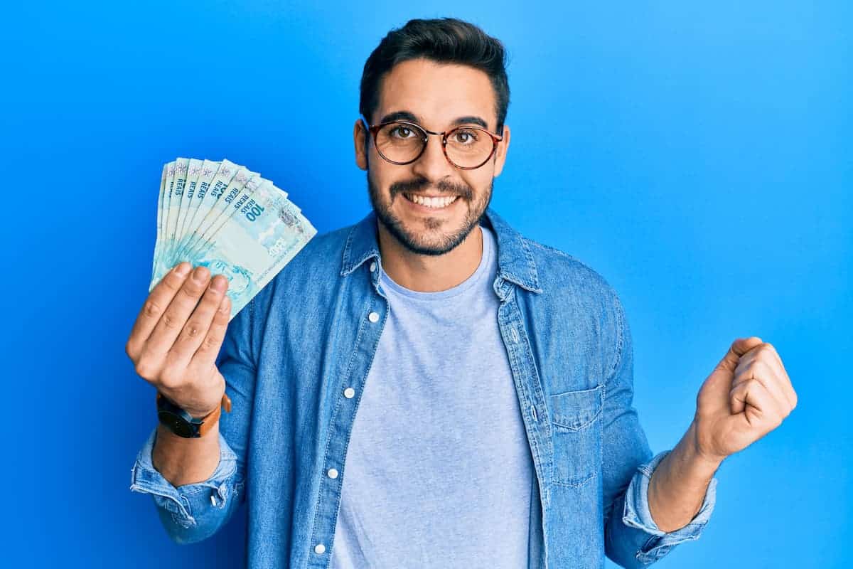 Brasileiro segurando dinheiro na mão direita e comemorando