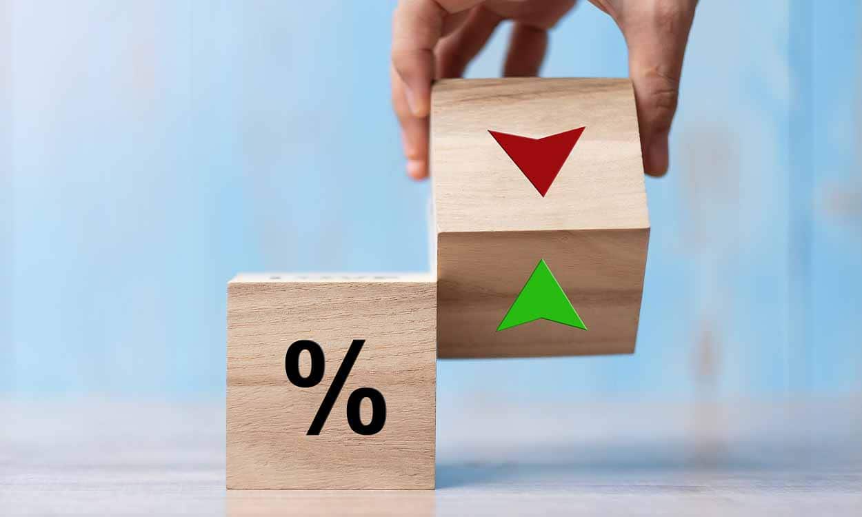 Dois cubos de madeira com símbolo de percentual de setas em vermelho e verde, simbolizando as taxas de juros IPTUbancos