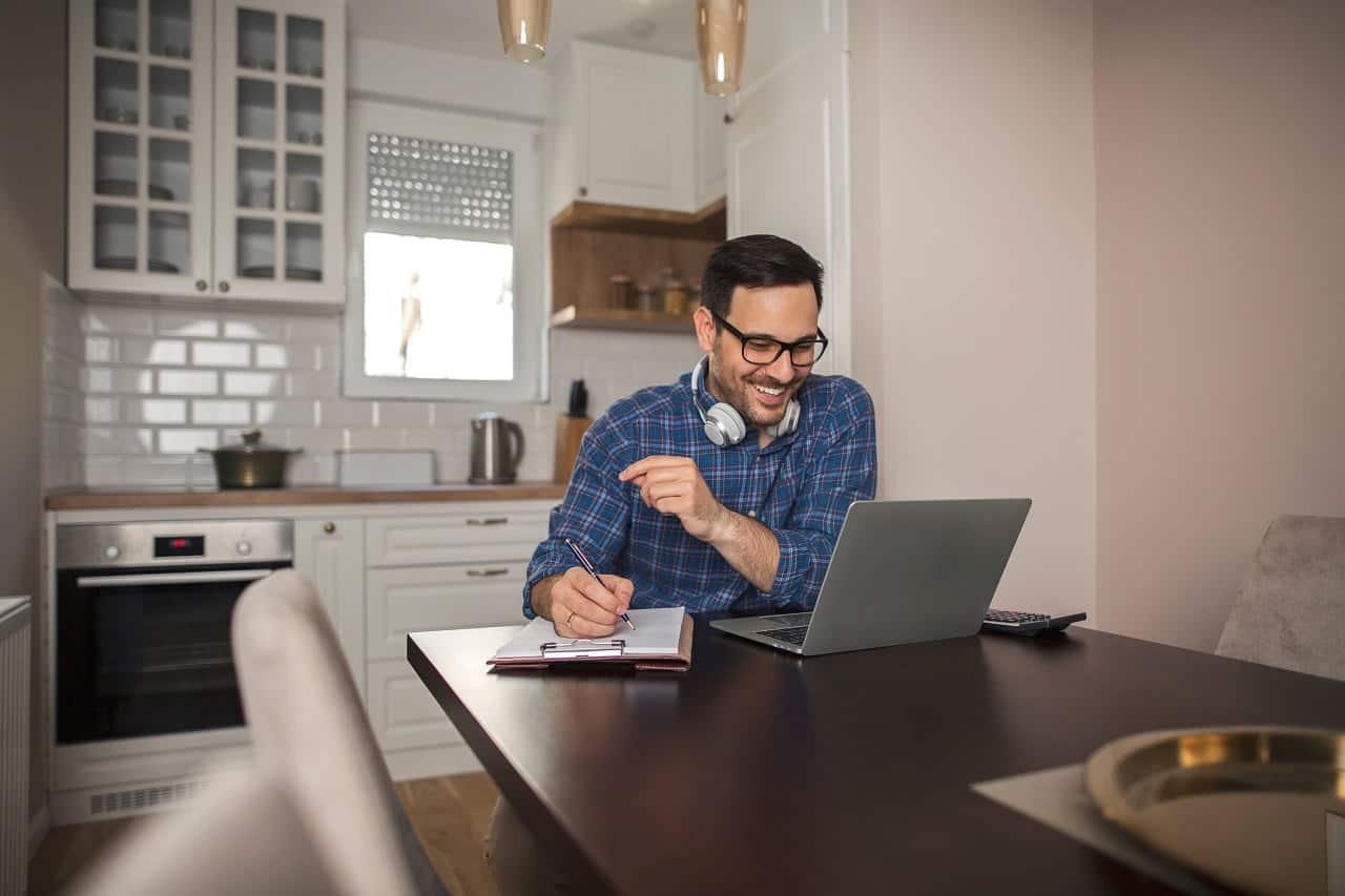 Homem sorrindo, trabalhando em home office.