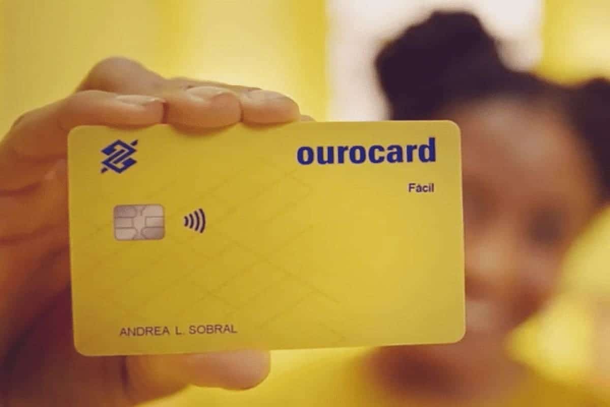 Moça segurando um cartão Ourocard do Banco do Brasil