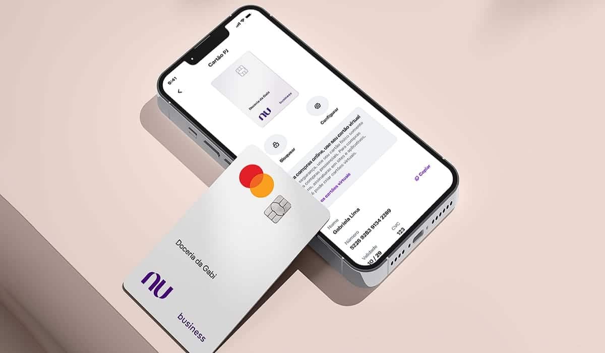 Imagem do cartão de crédito da conta PJ do Nubank por cima de um celular com o app do banco digital aberto