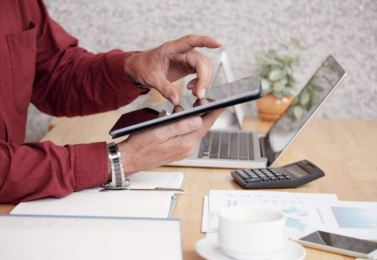 Homem mexendo no tablet em cima de uma mesa com papeis samsung tab