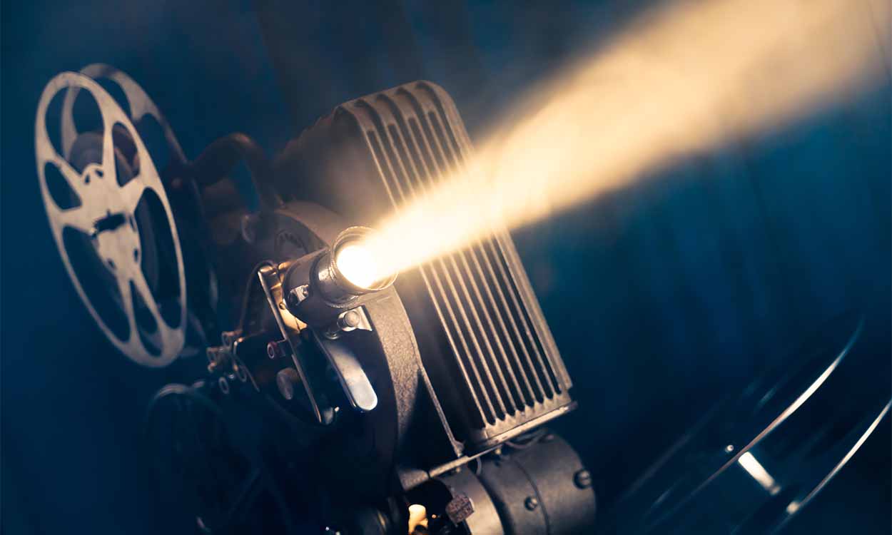 Imagem de um reprodutor de filmes de cinema. Ele projeta um feixe de luz amarelo para frente