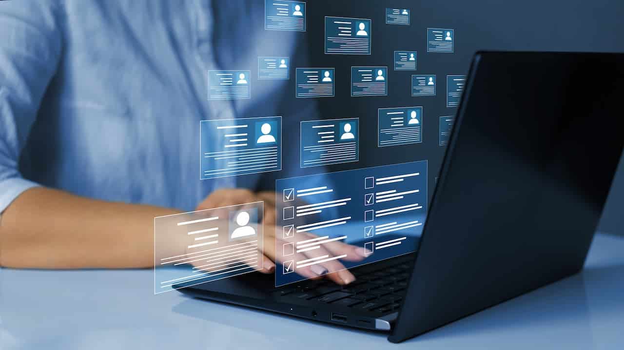 Pessoa mexendo no notebook com vários cadastros saindo da tela indicando várias inscrições